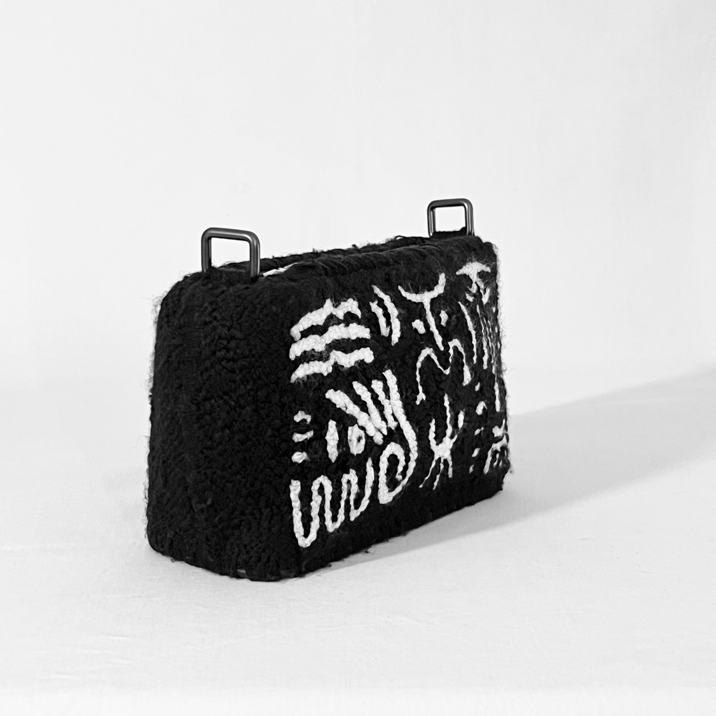 Angled view of Ohpunch Pochette Water Cipher DIY punch needle bag with abstract water-inspired symbols.